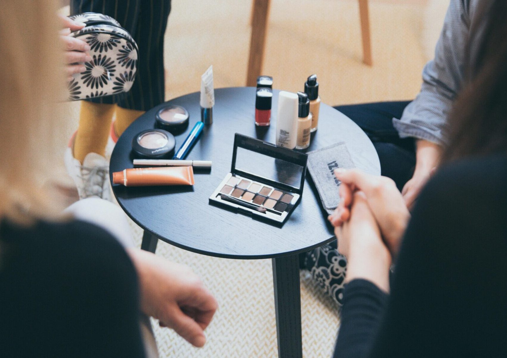 Women gathered around a table applying cosmetics, fostering a collaborative workspace.